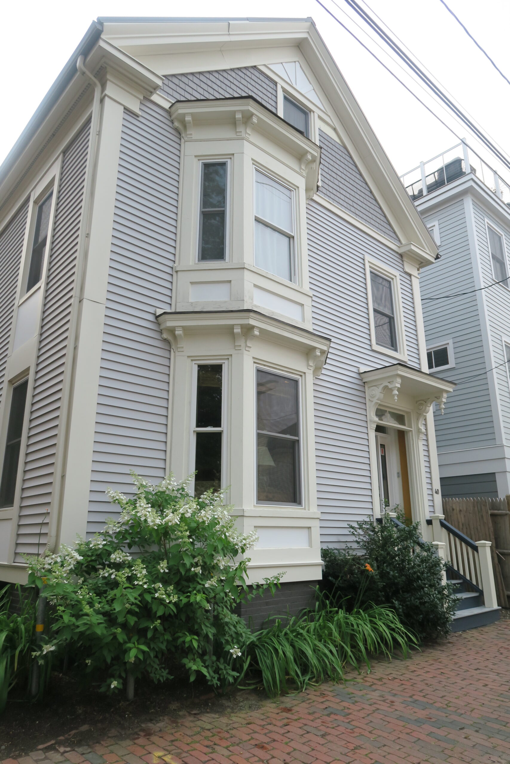 The exterior of Clayton's House located on O'Brion Street in Portland, Maine. The house is light blue with green trim and large green bushes on the front.